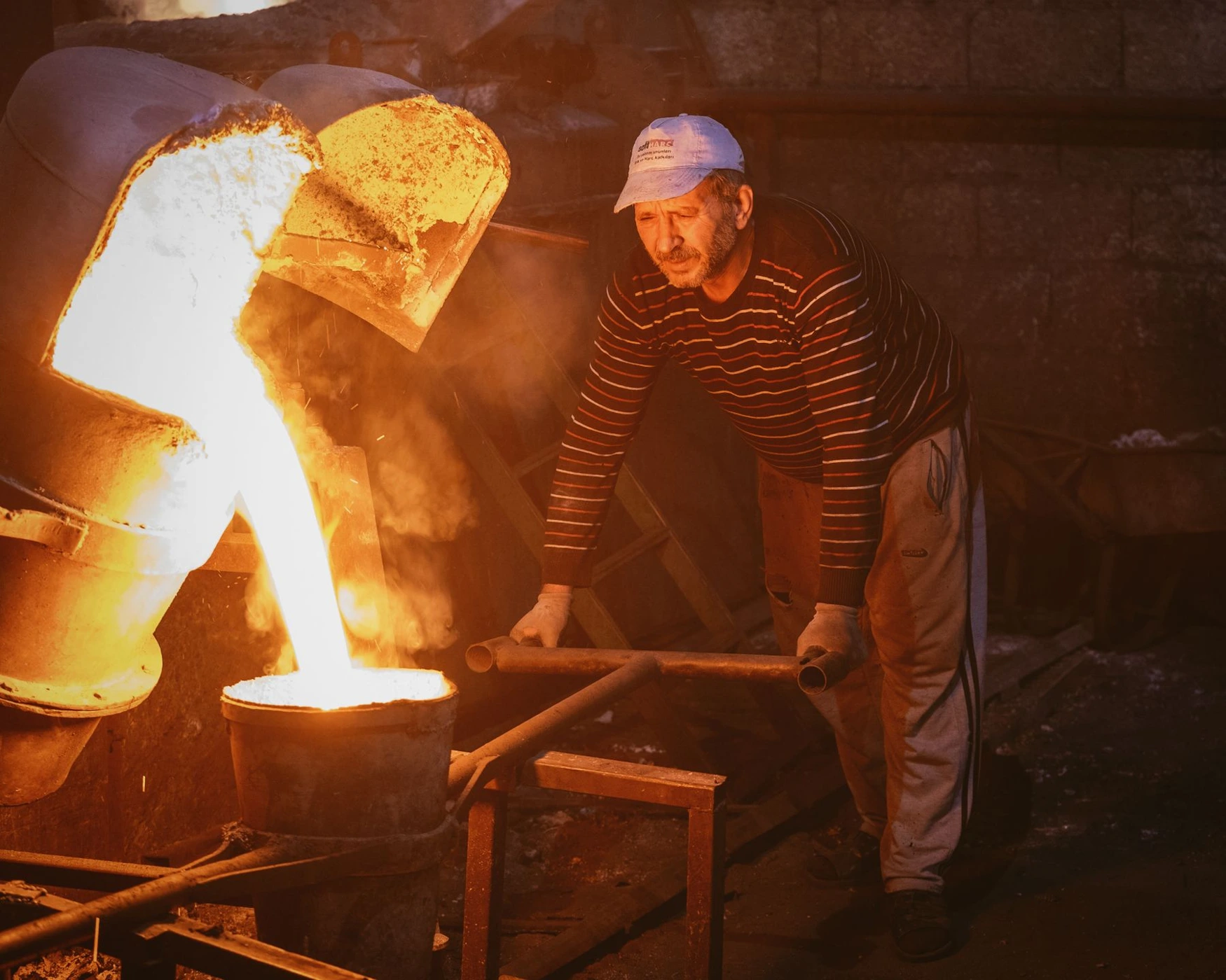 Foundry worker pouring molten metal into a mould